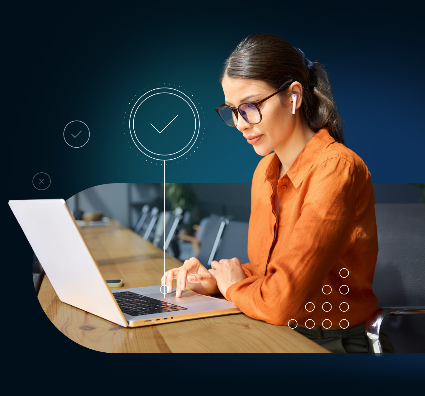 Woman working on a laptop with earphones on a long conference room table