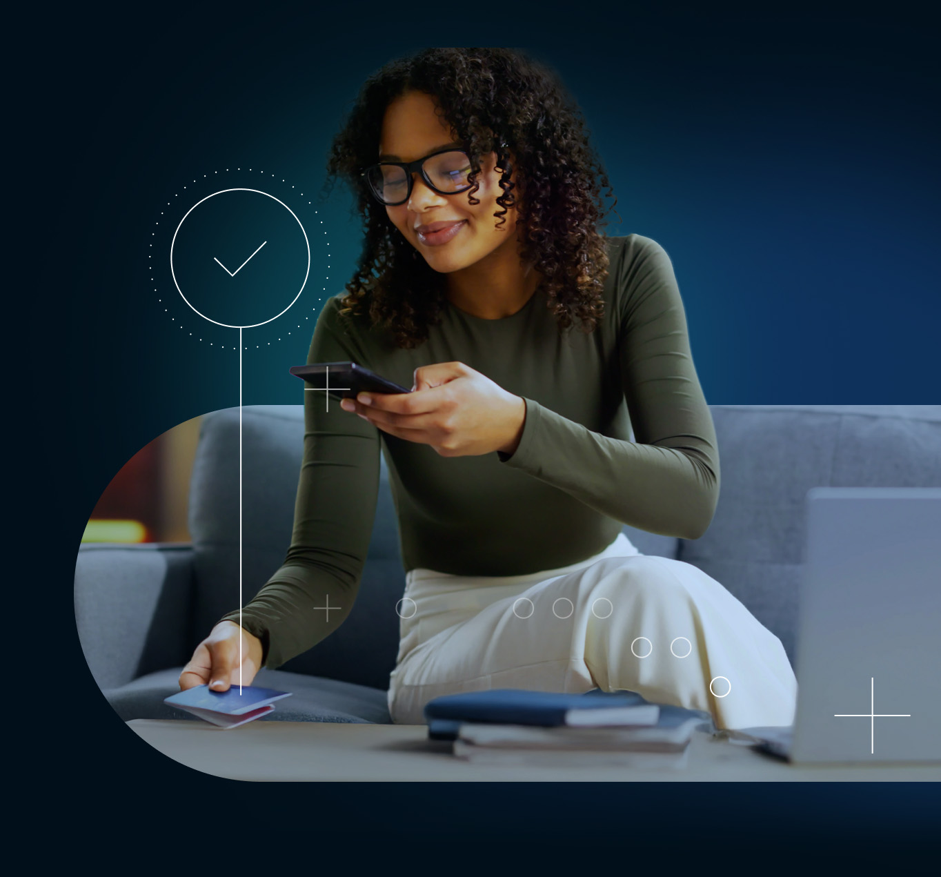 Seated young woman holding her smartphone in left hand and credit cards in the other